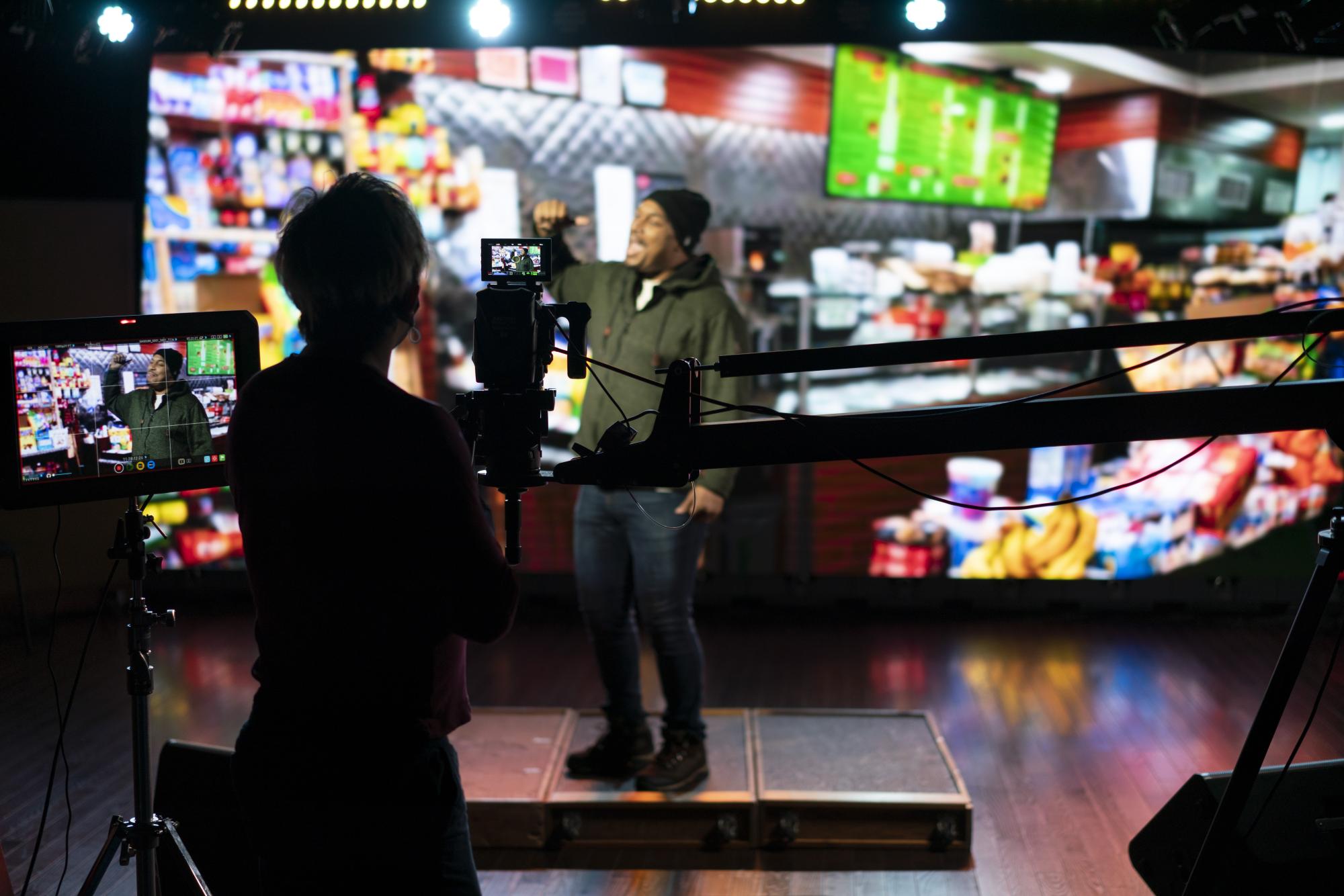 A cameraperson uses a Red Camera, jib and screen viewer to film a performer in front of an LED wall.